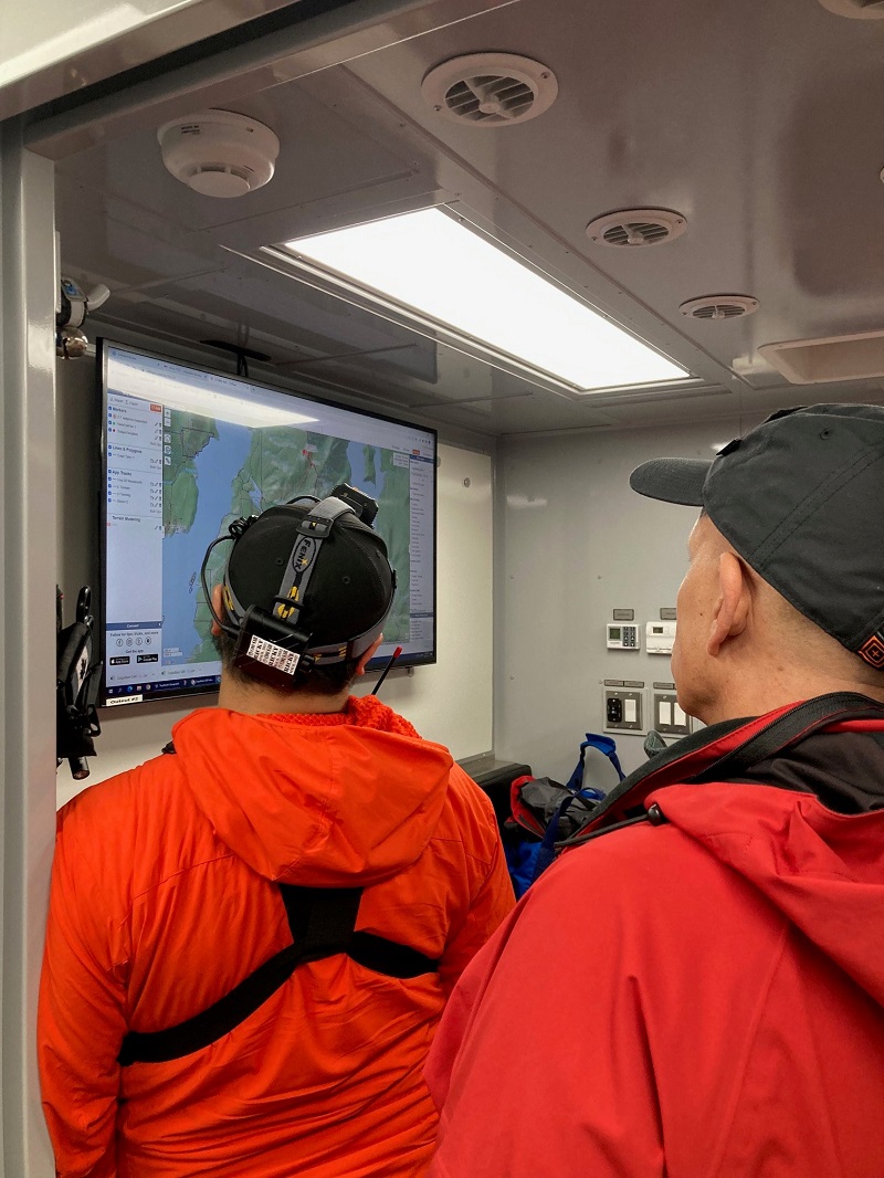 Deux membres de l’équipe de Recherche et Sauvetage de Coquitlam consultent une carte du secteur depuis l’intérieur du véhicule de commandement