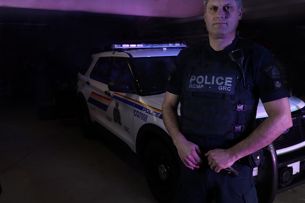 Sergeant Brenton Brady standing beside a police car